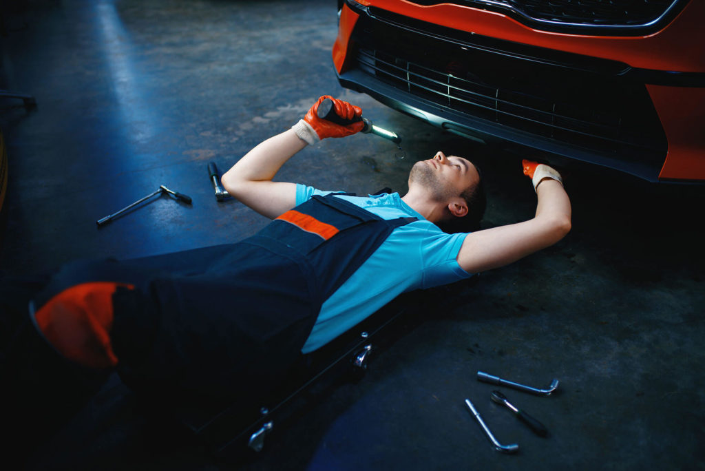 Worker lying under the vehicle, warranty work service